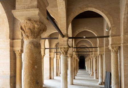 Couloir avec colonnade en pierre voûtée encerclant la cour intérieure de la mosquée d'Uqba dans la ville tunisienne de Kairouan. Architecture islamique traditionnelle