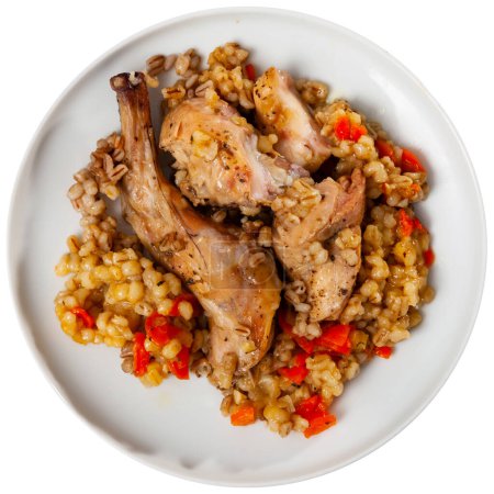 Traditional pearl barley porridge with stewed vegetables and fried rabbit on a plate. Isolated over white background