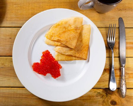 Crêpes au caviar rouge dans une assiette plate. Cuisine traditionnelle russe