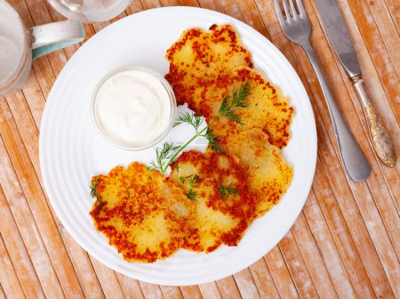 Fried grated potato pancakes with sour cream and dill, traditional Belarusian dish draniki