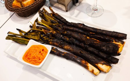 Appetizing national dish of Catalan cuisine called Calso, made from white onions, served with Romesco sauce