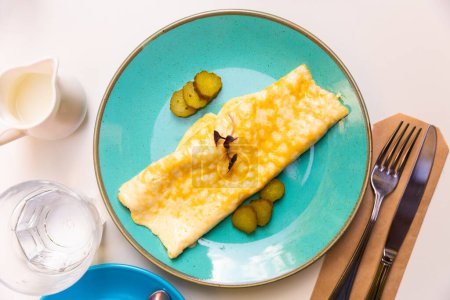 Omelette fine servie avec des tranches de concombre marinées garnies de microvert servi au petit déjeuner..