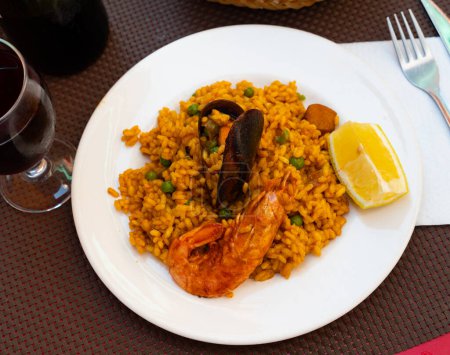Traditionelles spanisches Gericht ist Paella mit Meeresfrüchten aus Reis mit Safran und Weichtieren, dekoriert mit einer Zitronenscheibe