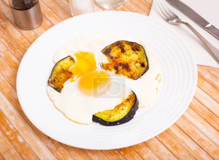 Gesundes Mittagessen aus Spiegeleiern mit flüssigem Eigelb und Auberginenscheiben auf Teller serviert ..