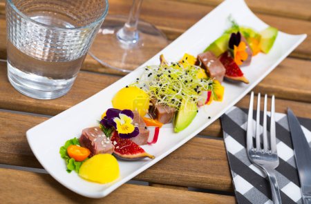 Köstlicher leicht gebratener Thunfisch mit Sesam bestreut auf weißem Teller serviert mit einer Mischung aus Obst, Gemüse und Gemüse