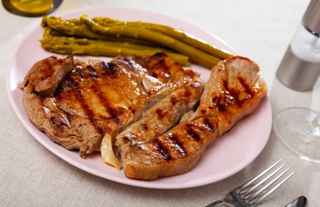 Spicy well done roasted veal steak served with asparagus