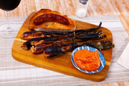 Collation espagnole populaire est délicieux calsot avec sauce Romesco, et saucisse traditionnelle butifarra servi sur du pain grillé