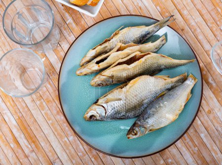 Dried salted caspian roach fish on light wooden background, traditional russian snack