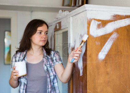 Smiling woman paints closet at home during repairs indoor