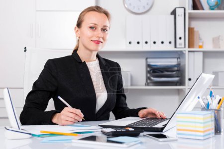 Cheerful woman working in the office at the laptop