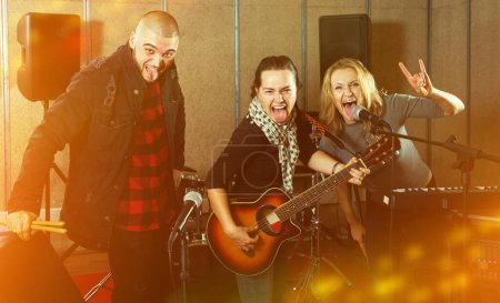 Ausdrucksstarke Gruppe erwachsener Rockmusiker posiert mit Instrumenten im Tonstudio