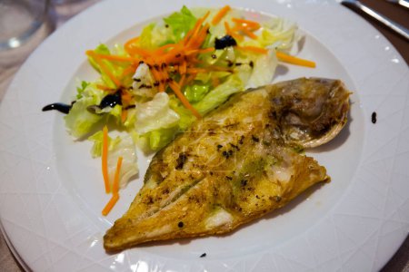 Grilled dorada garnished with salad of lettuce, carrot and balsamic