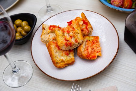 Assiette avec une collation catalane de pain aux tomates...