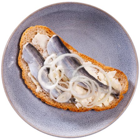 On top of greased bread is slices of lightly salted herring. Sandwich with butter and fish, decorated with ring of garden onion. Isolated over white background