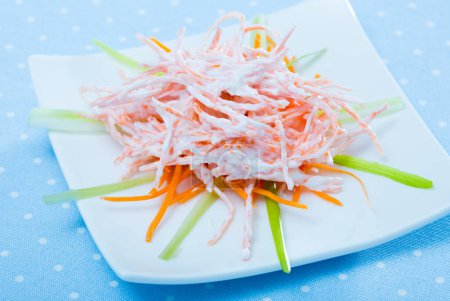 Healthy fresh carrot salad with sour cream and garlic served on white plate..
