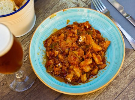 Guiso de bacalao con verduras pimientos, tomates, ajo y cebollas de cerca en un tazón sobre la mesa