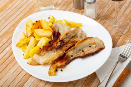 Image de bacon de porc frit sur une assiette et frites.