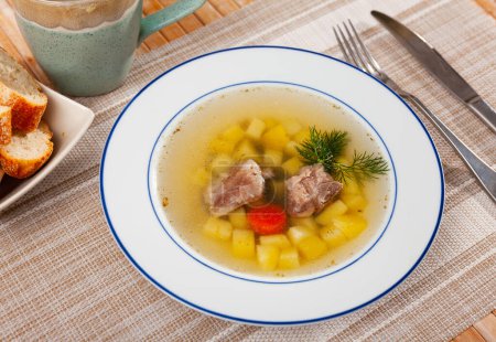 Deliciosa sopa gruesa de estilo rústico cocinada en caldo de carne con cerdo y verduras.