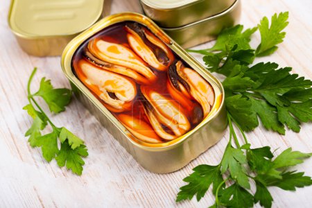 Photo de savoureuses moules marinées en boîte ouverte servie avec des légumes et du citron à table