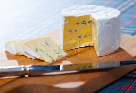 Delicate soft blue cheese served on wooden cutting board ..