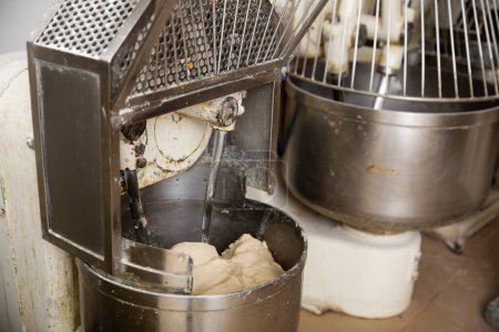 Making bread dough in kneading machine. Professional bakery equipment