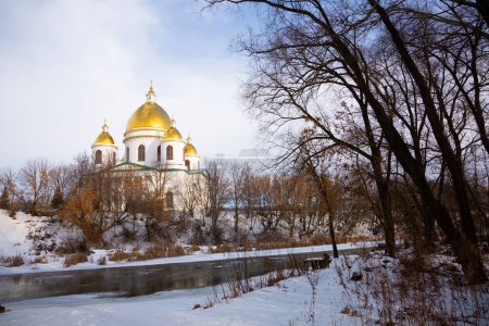 Scenic winter landscape overlooking majestic building of Trinity Cathedral with golden domes on bank of Tsna river in Russian town of Morshansk