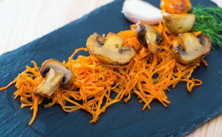 Fried mushrooms served with sliced carrots and fresh dill