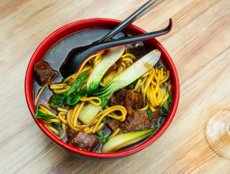 Chinese beef soup with noodles and green mustard cabbage served in a bowl
