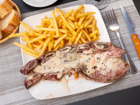 Steak barbeque with pepper dished up with French fries with necessary table laying