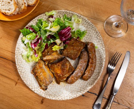 Fried butifarra sausages with fried ribs. Food is complemented by fresh colorful cabbage salad