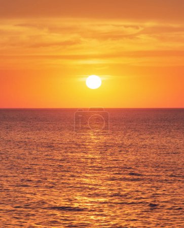 Foto de Puesta de sol brillante con gran sol amarillo bajo la superficie del mar - Imagen libre de derechos