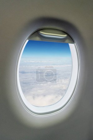 Airplane window. Sky, sun and clouds view.