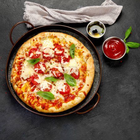 Freshly baked pizza on dark background. Tasty homemade food concept. Top view, copy space
