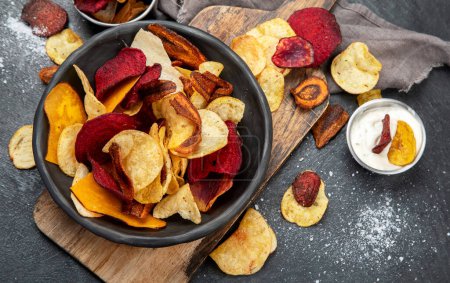 Photo for Bowl of healthy colorful vegetable chips on dark background, top view - Royalty Free Image