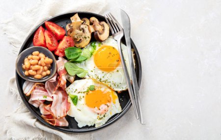 Photo for Full English breakfast with fried egg, sausage, bacon and toast on grey background. Top view, copy space - Royalty Free Image