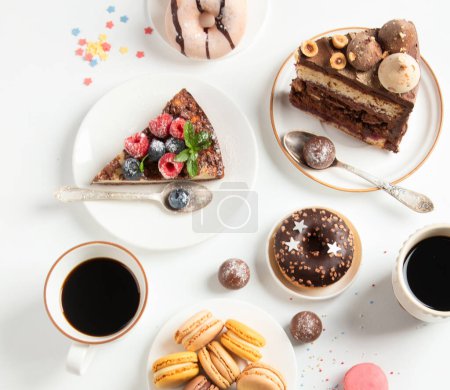 Foto de Mesa con varias galletas, rosquillas, pasteles, tartas de queso y tazas de café sobre fondo blanco. Deliciosa mesa de postres. Vista superior, plano - Imagen libre de derechos
