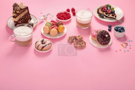 Téléchargez les photos : Table avec divers biscuits, beignets, gâteaux, gâteaux au fromage et tasses à café sur fond rose. Délicieuse table à dessert. espace de copie - en image libre de droit