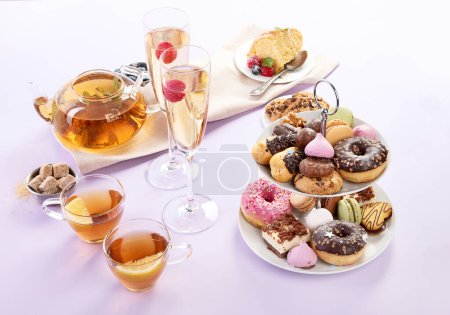 Traditioneller englischer Tee. Nachmittagstee mit einer Auswahl an Süßigkeiten auf violettem Hintergrund. Urlaubskonzept