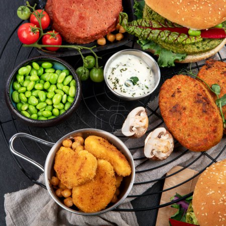 Photo for Plant-based food concept-vegan burgers, sausages, vegetarian nuggets, fresh vegetables and sauces on a dark background. top view. - Royalty Free Image