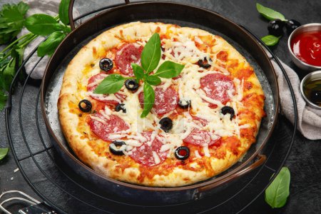 Foto de Freshly baked pepperoni pizza on dark background. Tasty homemade food concept. - Imagen libre de derechos