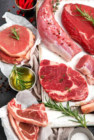 Photo for Different types of raw meat - beef, pork, lamb, chicken on dark background. Top view, flat lay - Royalty Free Image