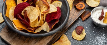 Photo for Bowl of healthy colorful vegetable chips on dark background, top view - Royalty Free Image