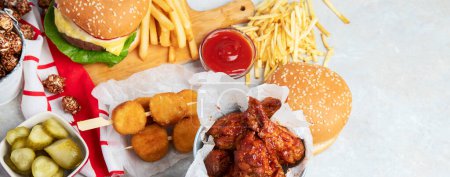 Foto de Various of american food, French fries, hamburgers, nuggets, hotdog, chips, popcorn, sauces on a white background, top view. Panorama with copy space. - Imagen libre de derechos