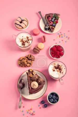 Téléchargez les photos : Table avec divers biscuits, beignets, gâteaux, gâteaux au fromage et tasses à café sur fond rose. Délicieuse table à dessert. Vue de dessus, plan plat - en image libre de droit