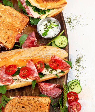 Téléchargez les photos : Assorted delicious baguette sandwiches. Various kinds of club sandwiches on a white background. Top view. - en image libre de droit