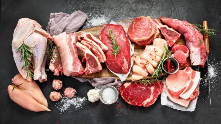 Verschiedene Arten von rohem Fleisch - Rind, Schwein, Lamm, Huhn auf dunklem Hintergrund. Ansicht von oben
