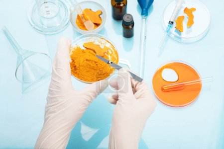 Photo for Medicine research of curcuma properties with the help of laboratory equipment, woman in gloves testing turmeric powder. Top view - Royalty Free Image