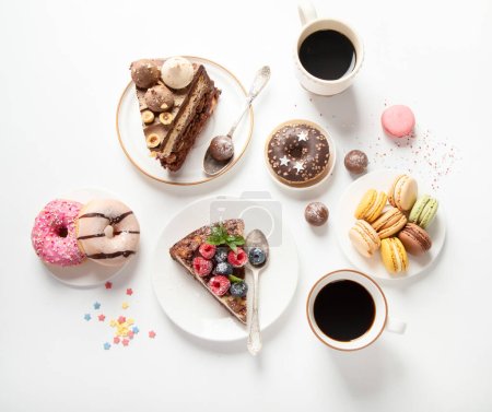 Foto de Mesa con varias galletas, rosquillas, pasteles, tartas de queso y tazas de café sobre fondo blanco. Deliciosa mesa de postres. Vista superior, plano - Imagen libre de derechos