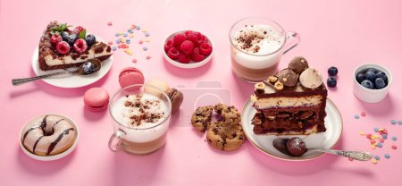 Foto de Mesa con varias galletas, rosquillas, pasteles, tartas de queso y tazas de café sobre fondo rosa. Deliciosa mesa de postres. - Imagen libre de derechos