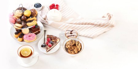 Téléchargez les photos : Porte-gâteaux avec macarons, mini gâteaux, biscuits pour le thé. Panorama avec espace de copie. - en image libre de droit